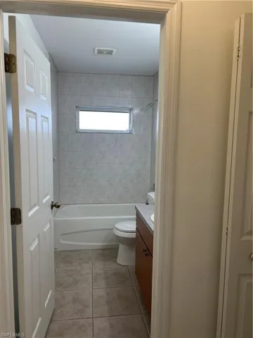 Bathroom with vanity, toilet, tile patterned flooring, and shower / washtub combination