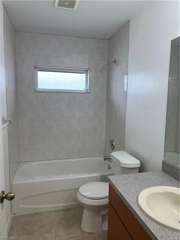 Bathroom featuring tile patterned floors, vanity, toilet, and shower / bathtub combination