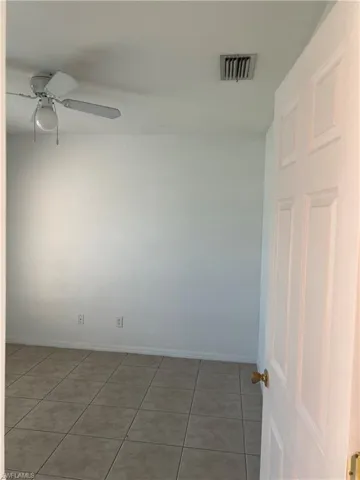 Empty room with a ceiling fan, baseboards, tile patterned floors, and visible vents