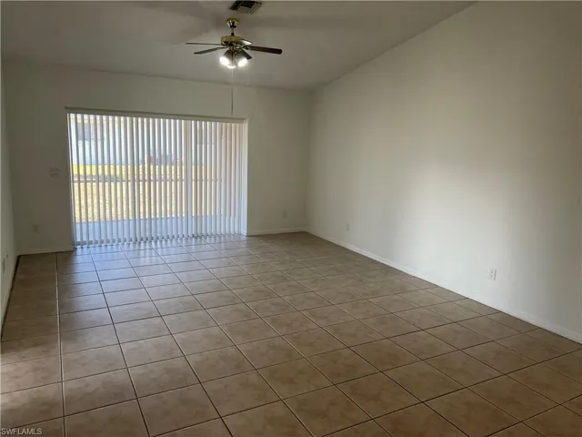 Empty room with baseboards, a ceiling fan, visible vents, and tile patterned floors