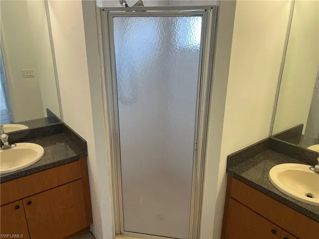Full bathroom with a sink, two vanities, and a shower stall