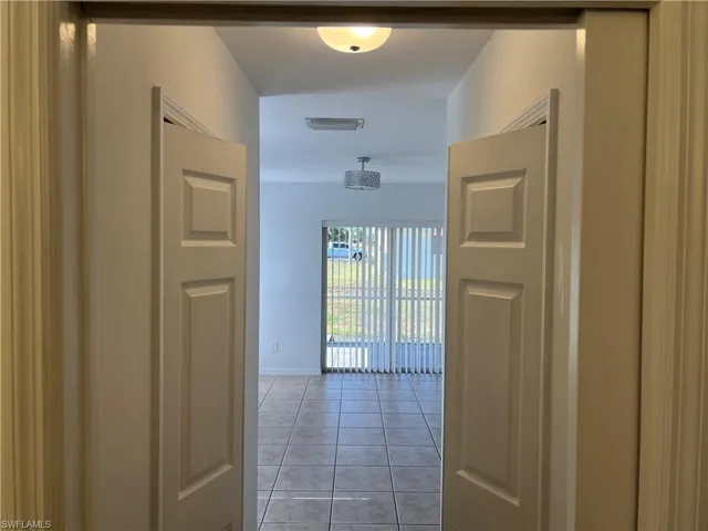Corridor with light tile patterned floors, visible vents, and baseboards