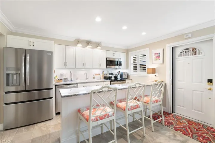 Kitchen featuring appliances with stainless steel finishes, white cabinets, a kitchen bar and ornamental molding