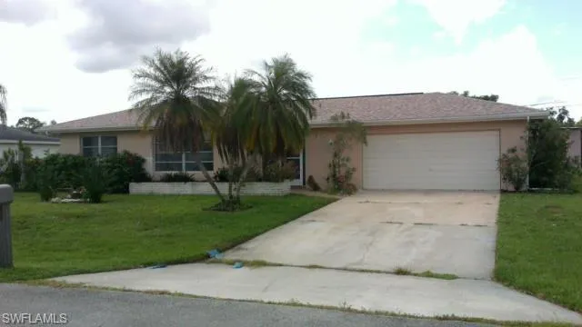 View of front of home with concrete driveway, an attached garage, a front lawn, and stucco siding