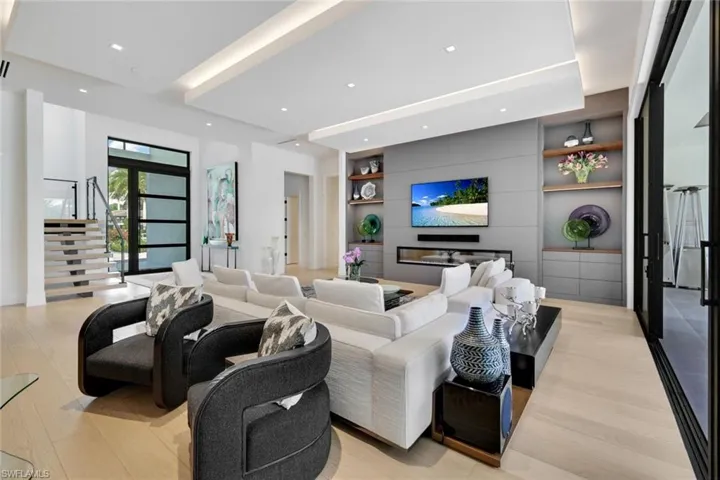 Living area featuring built in features, light wood-style floors, and stairs