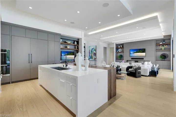 Kitchen featuring modern cabinets, built in features, light wood-style flooring, a sink, and a center island with sink