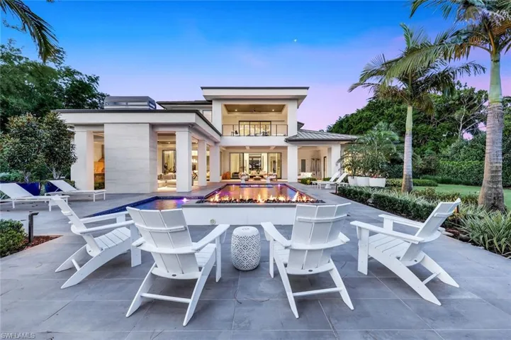 Back of property featuring a balcony, a patio, an outdoor fire pit, and stucco siding