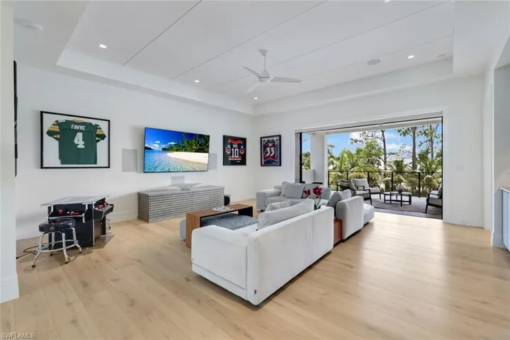 Living area with a tray ceiling, ceiling fan, light wood-style flooring, baseboards, and recessed lighting