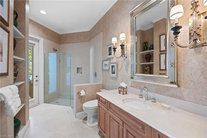 Bathroom with vanity, toilet, ornamental molding, and a shower with door