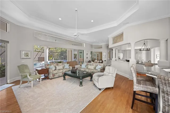 Living room featuring ceiling fan with notable chandelier, ornamental molding, a tray ceiling, and light hardwood / wood-style flooring