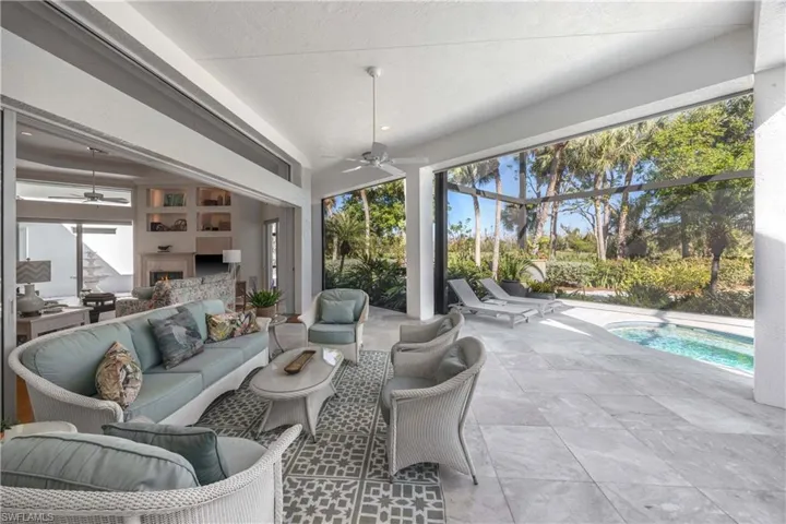 Sunroom / solarium featuring ceiling fan, exterior fireplace, and a swimming pool