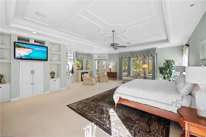 Bedroom with ceiling fan, light colored carpet, ornamental molding, and coffered ceiling