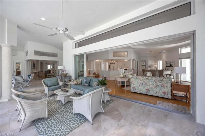 Living room with a textured ceiling, decorative columns, high vaulted ceiling, and ceiling fan