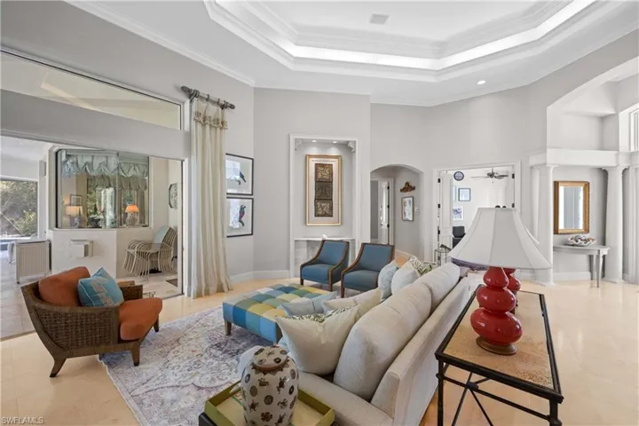 Living room with a high ceiling, a raised ceiling, ceiling fan, and ornamental molding