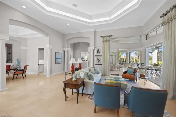Living room featuring ceiling fan, a raised ceiling, and ornamental molding