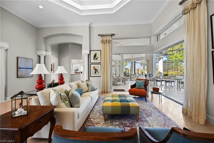 Living room with ornate columns, crown molding, light tile patterned floors, and ceiling fan