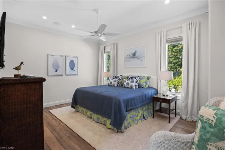 Bedroom with hardwood / wood-style floors, ceiling fan, and ornamental molding