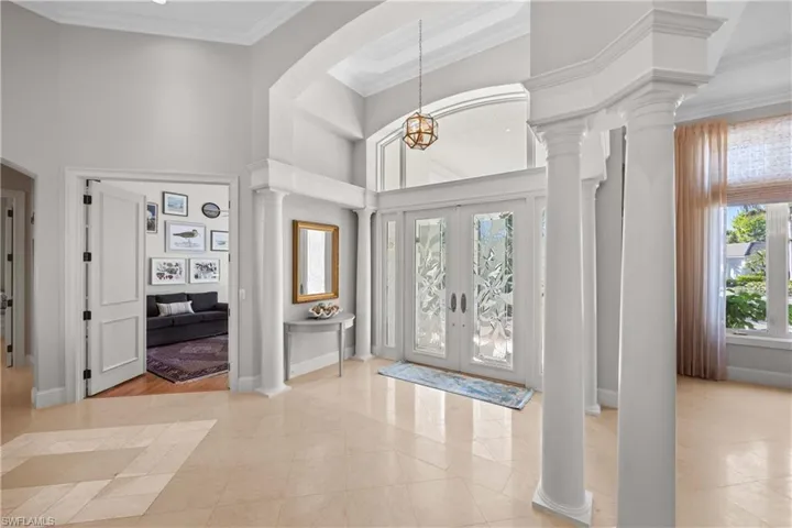 Entryway with a towering ceiling, crown molding, light tile patterned floors, and french doors