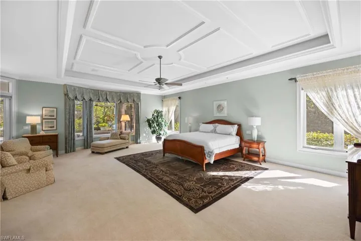 Carpeted bedroom featuring ceiling fan and coffered ceiling