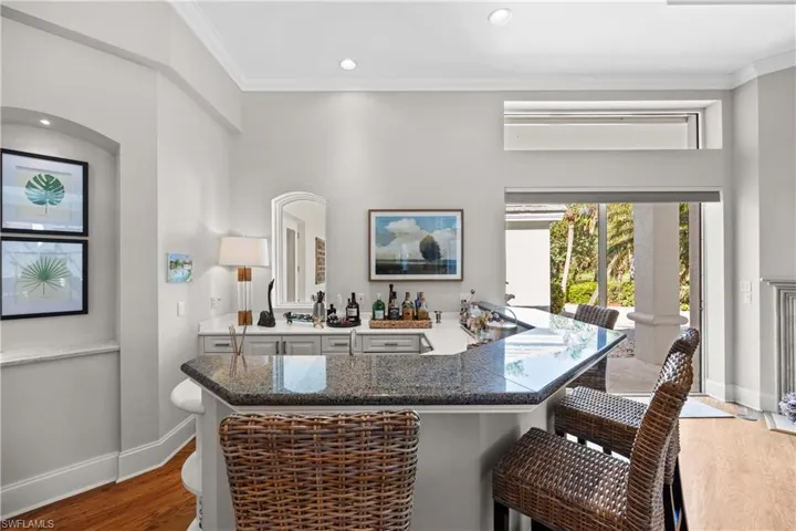 Bar featuring wood-type flooring and ornamental molding