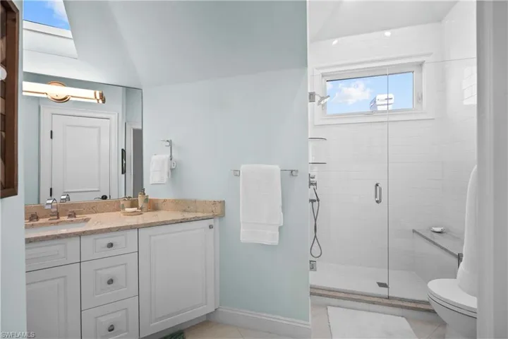 Bathroom with toilet, vanity, tile patterned floors, and a shower with door