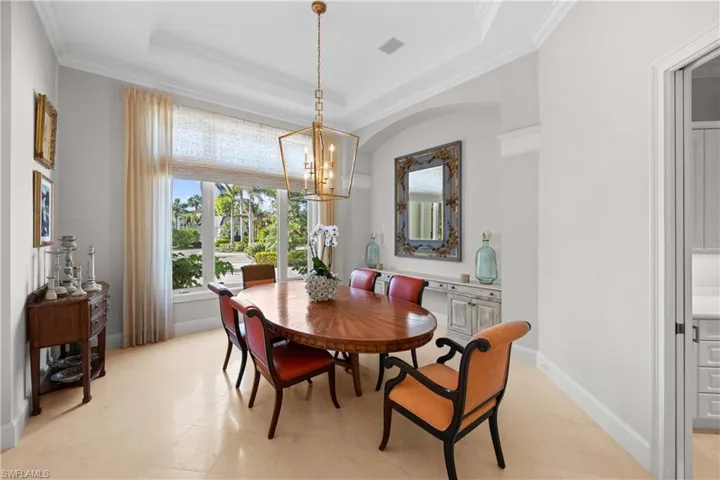Dining room featuring a tray ceiling, an inviting chandelier, and crown molding