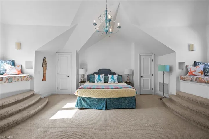 Bedroom featuring carpet floors, lofted ceiling, and a notable chandelier