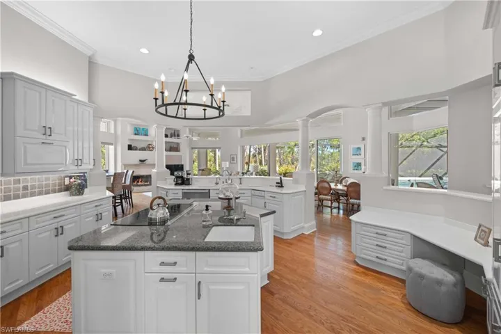 Kitchen with light wood-type flooring, black electric stovetop, a center island, and hanging light fixtures