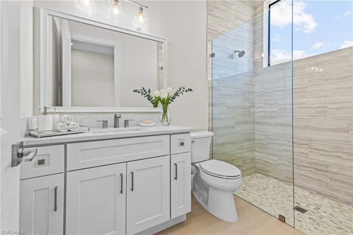 Full bathroom with walk in shower, vanity, and light wood-style floors