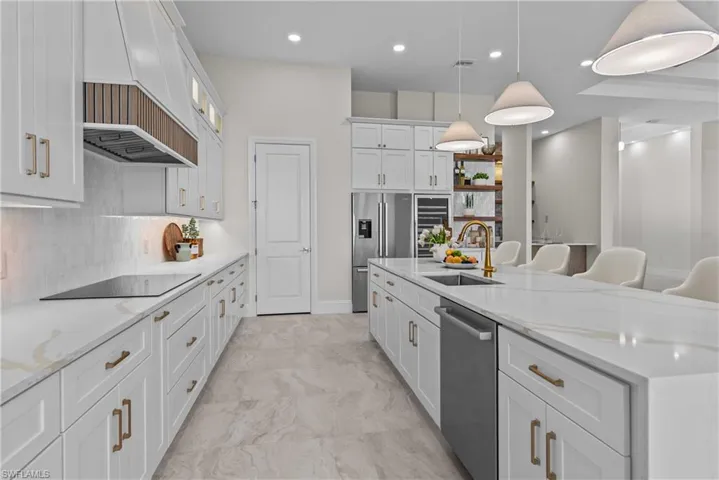Kitchen featuring light stone countertops, white cabinets, tasteful backsplash, a kitchen breakfast bar, and recessed lighting