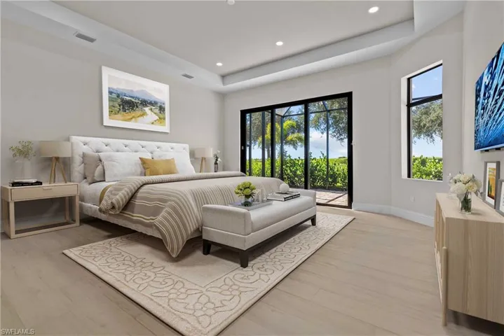 Bedroom with a raised ceiling, access to outside, light wood-style flooring, and recessed lighting