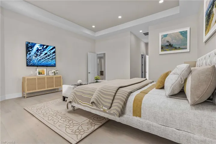 Bedroom with a tray ceiling, wood finished floors, and recessed lighting