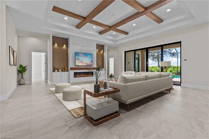 Living room with coffered ceiling, beam ceiling, a high end fireplace, and recessed lighting