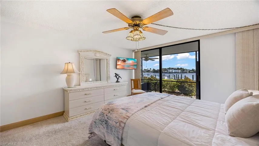 Bedroom with a textured ceiling, a ceiling fan, light colored carpet, access to exterior, and floor to ceiling windows