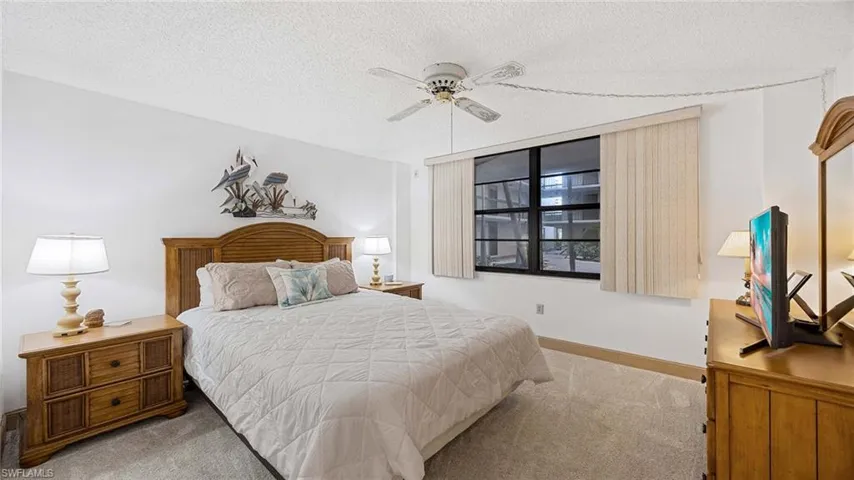 Carpeted bedroom featuring a textured ceiling and ceiling fan