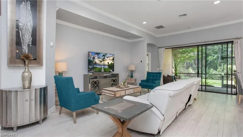 Living area with wood finished floors, arched walkways, ornamental molding, and recessed lighting