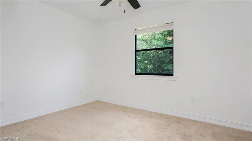 Carpeted spare room featuring a ceiling fan and baseboards