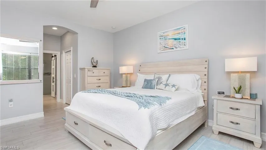 Bedroom with arched walkways, light wood-style flooring, ceiling fan, and a closet