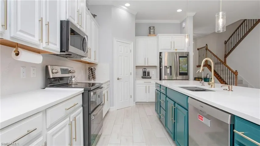 Kitchen featuring blue cabinetry, stainless steel appliances, white cabinets, crown molding, and light countertops