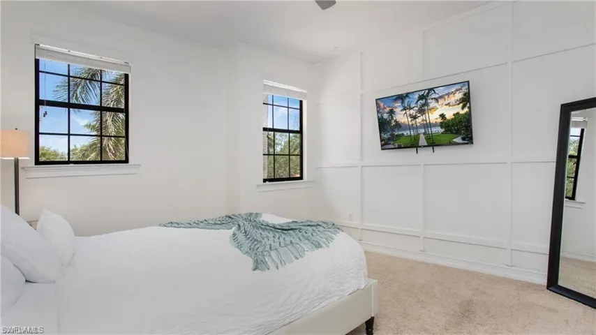 Bedroom featuring a decorative wall, multiple windows, and carpet floors