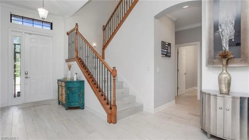 Foyer entrance featuring ornamental molding, arched walkways, stairway, and wood finished floors