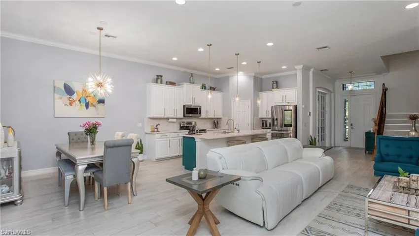Living room featuring light wood-type flooring, recessed lighting, crown molding, and stairs
