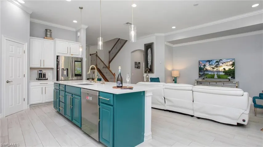 Kitchen featuring blue cabinets, open floor plan, white cabinetry, crown molding, and appliances with stainless steel finishes