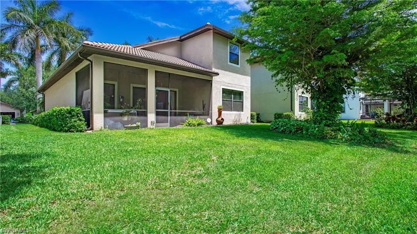 Back of house featuring stucco siding, a yard, a tiled roof, and a sunroom