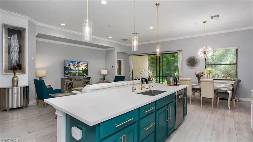 Kitchen featuring healthy amount of natural light, light wood finished floors, light countertops, recessed lighting, and ornamental molding