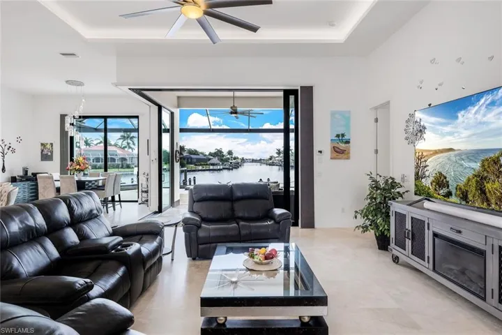Living area with a raised ceiling, a chandelier, and ceiling fan