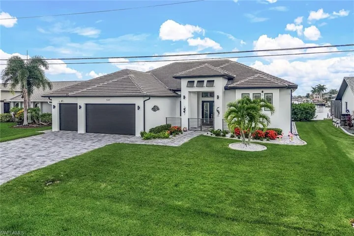 View of front facade with a front lawn, decorative driveway, a garage, stucco siding, and a tiled roof