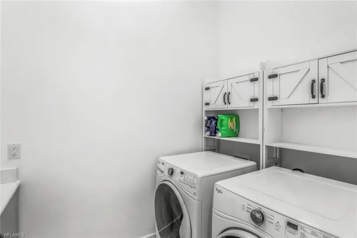 Washroom with cabinet space and washing machine and clothes dryer