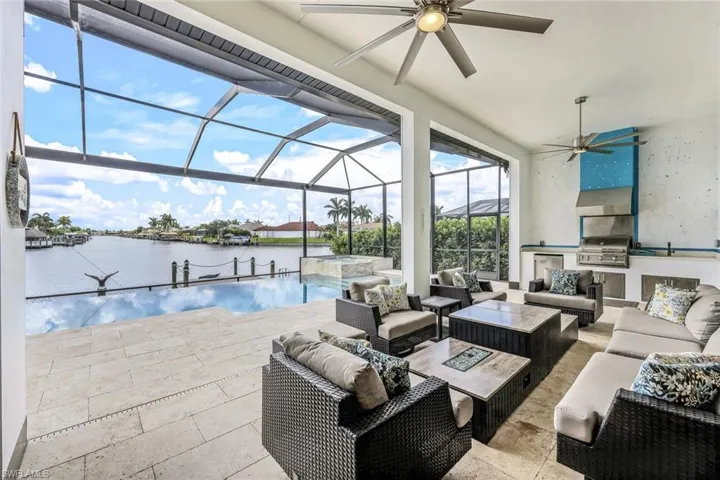 View of pool featuring a sunroom, an outdoor hangout area, a water view, an outdoor kitchen, and a patio area
