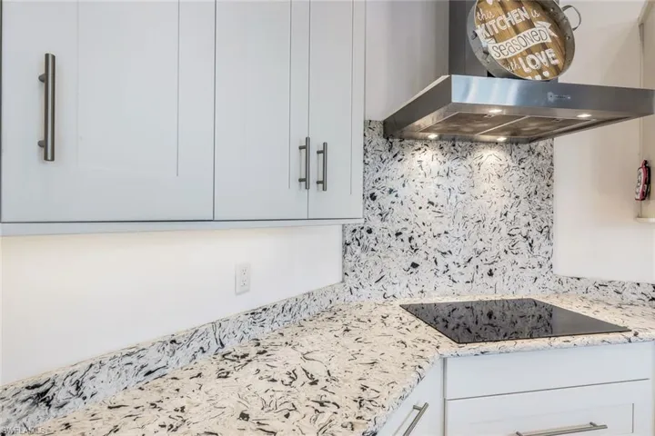 Kitchen featuring range hood, tasteful backsplash, and white cabinetry